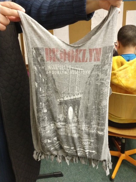 Ein Junge hält eine selbst gefertigte Tasche aus einem alten T-Shirt in der Hand